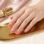 Hand with pink nail polish on a gold tray with a pink fabric background