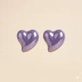 Pair of glossy purple puffy heart stud earrings with high-shine lacquer finish on beige background