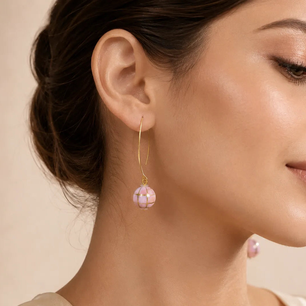 "Woman wearing pink mosaic bead drop earring with gold wire hook"