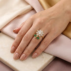 "Woman wearing gold daisy flower ring with green leaf accents on finger"