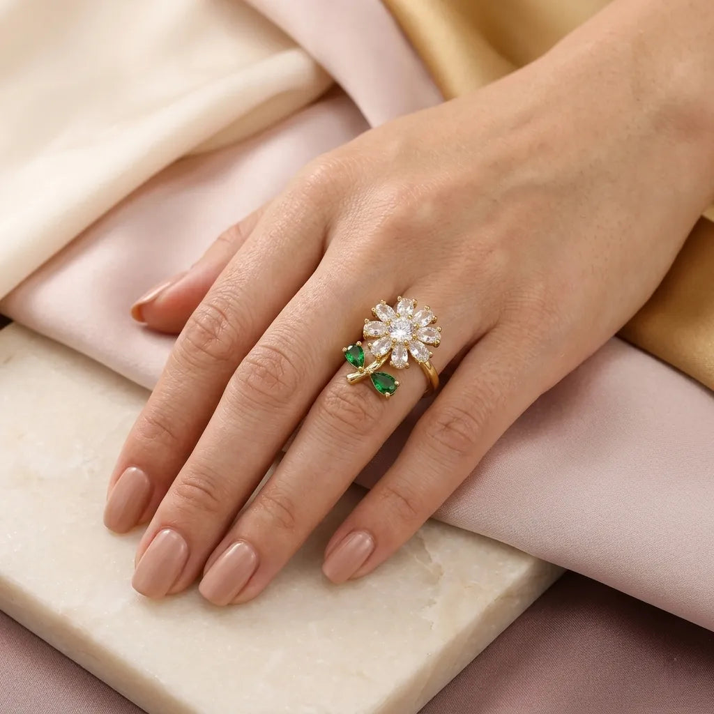 "Woman wearing gold daisy flower ring with green leaf accents on finger"