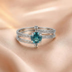 925 sterling silver split shank ring with round teal gemstone center, ribbed texture on double band, close-up on satin fabric