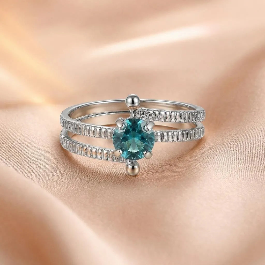 925 sterling silver split shank ring with round teal gemstone center, ribbed texture on double band, close-up on satin fabric