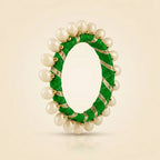 Close-up of green silk thread bangle with gold zari ribbon and pearl beads"