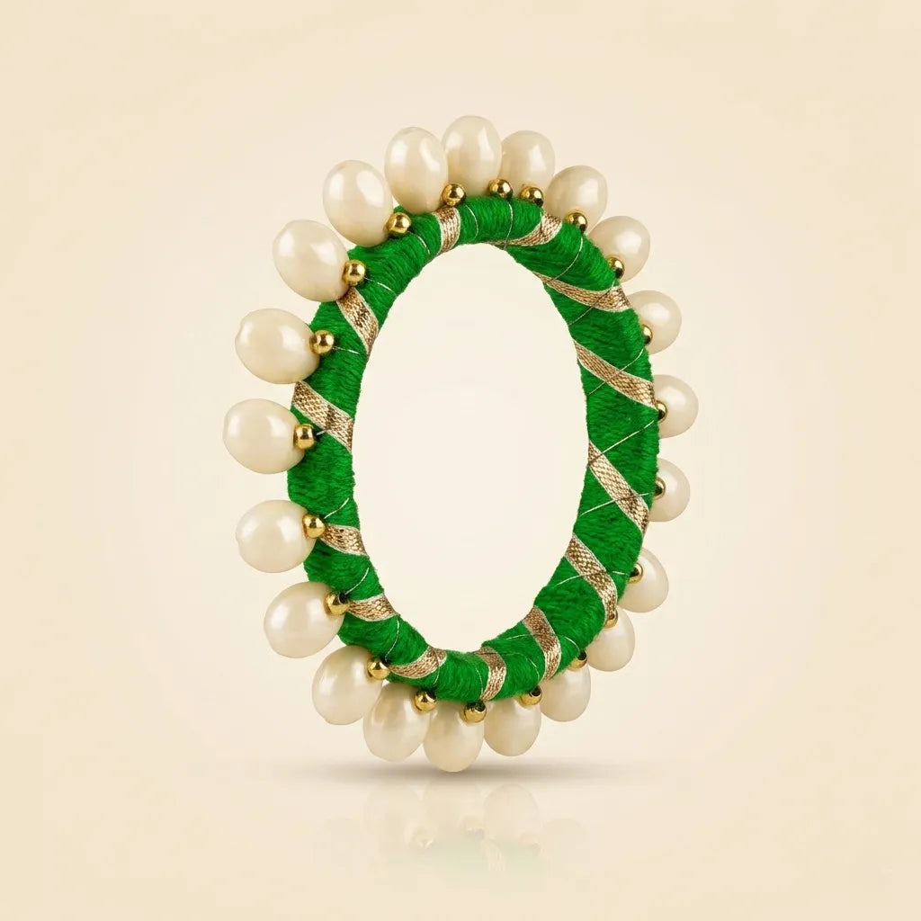Close-up of green silk thread bangle with gold zari ribbon and pearl beads"