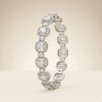 Two silver emerald cut cubic zirconia halo bangle bracelets overlapping on beige background showing octagonal link detail and brilliant crystal clarity