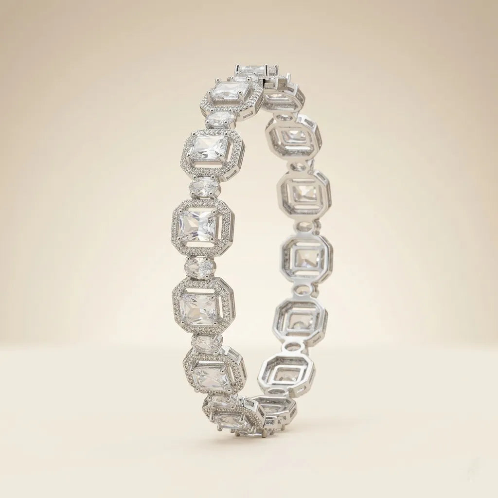 Two silver emerald cut cubic zirconia halo bangle bracelets overlapping on beige background showing octagonal link detail and brilliant crystal clarity