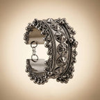Side view of oxidized silver tribal wide cuff bangle showing open-back construction hook clasp and full ghungroo ball drop fringe circumference