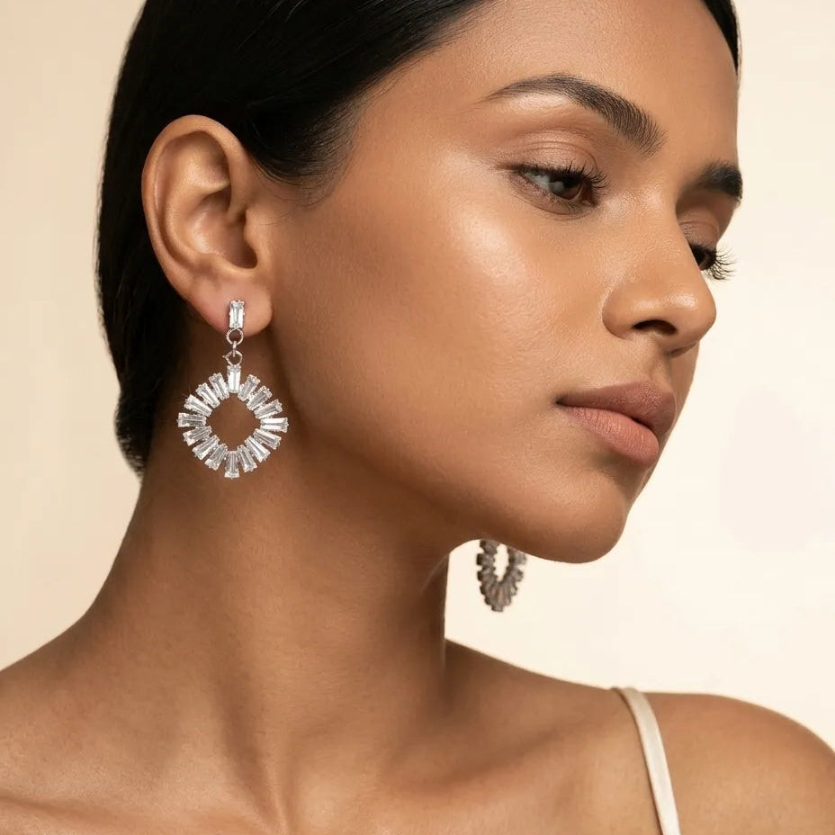 Woman wearing a pair of silver hoop earrings against a neutral background