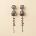 Pair of silver earrings with intricate designs on a beige background