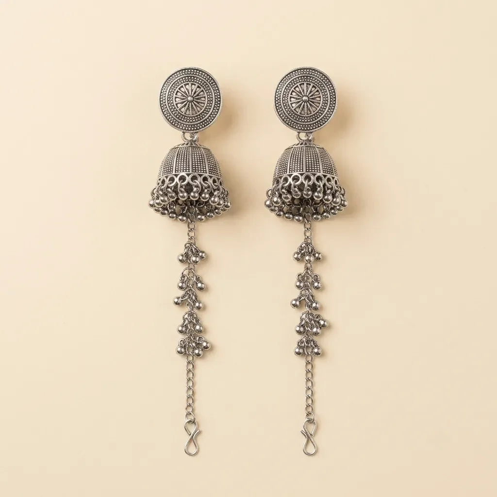 Pair of silver earrings with intricate designs on a beige background