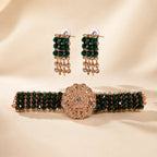 A matching jewelry set featuring a beaded bracelet and matching drop earrings, decorated with dark green faceted beads and rose gold-toned metal with clear rhinestones, displayed on a beige satin background.