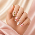 Woman's hand wearing sage green and pink floral daisy press on nails, close-up on fingertips