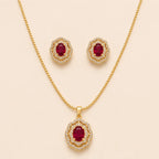 Gold ruby halo necklace and matching stud earrings laid flat on beige background