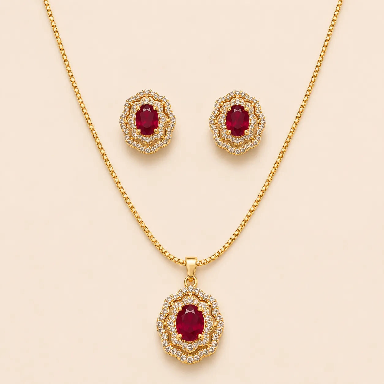 Gold ruby halo necklace and matching stud earrings laid flat on beige background
