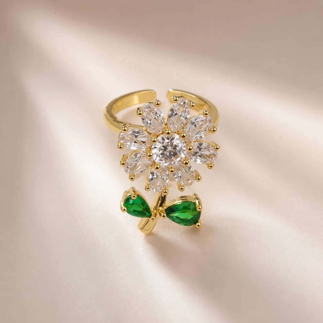  "Gold daisy flower ring with CZ petals and emerald green leaf accents"