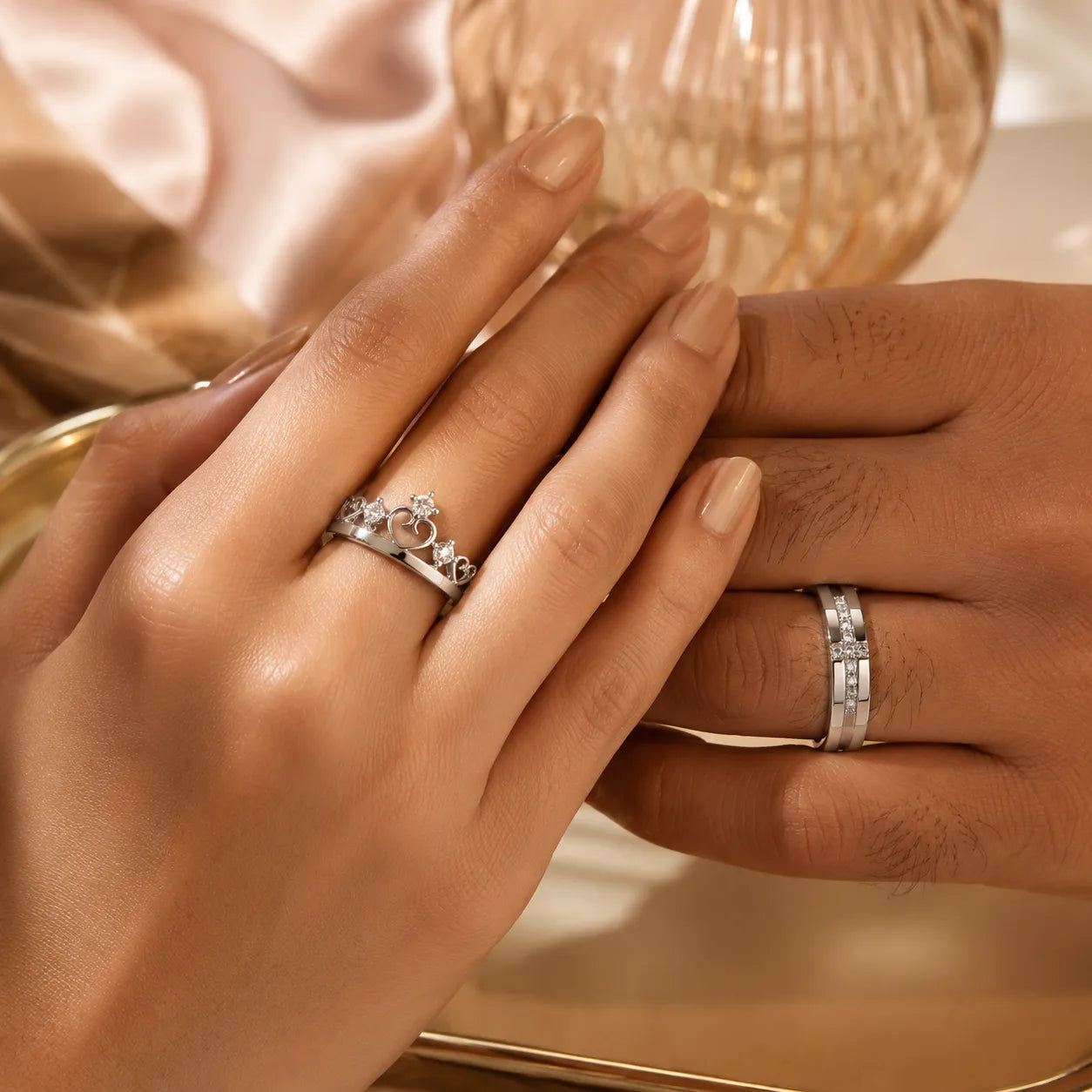 Couple wearing silver crown tiara heart ring (her) and wide CZ band ring (his) — matching couple ring set on both hands