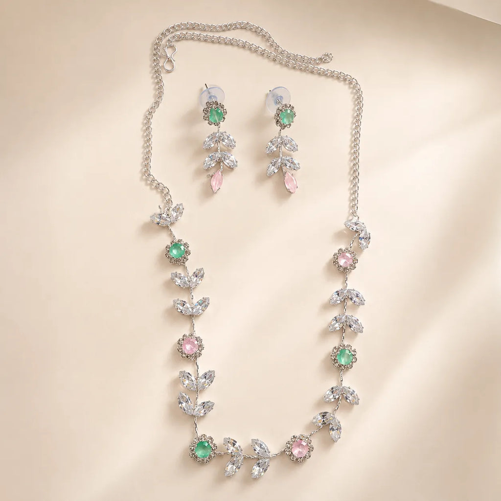 Silver crystal leaf vine necklace and earring set coiled on beige surface, showing extendable chain and flower details