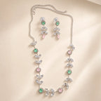 Silver crystal leaf vine necklace and earring set coiled on beige surface, showing extendable chain and flower details