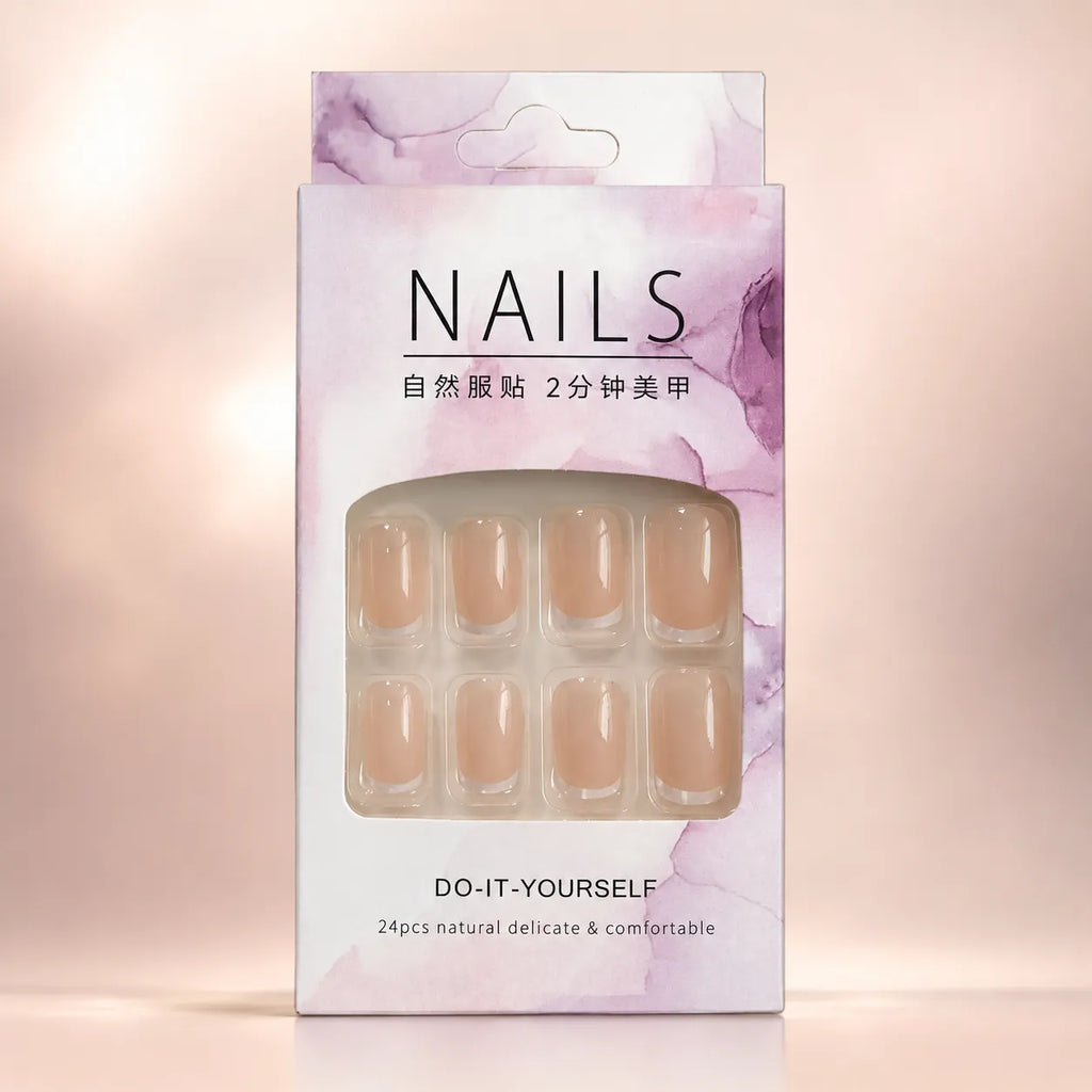 Eight sheer nude press on nails with glossy clear tips laid flat on beige background