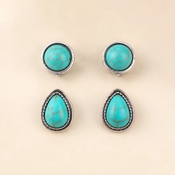 Flat lay of two turquoise earring pairs, round and teardrop shapes, antique silver trim
