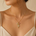 Woman wearing gold fairy pendant necklace with crystal detailing and pink flower charm, close-up necklace photo
