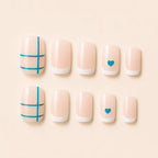 Set of 12 short square nude French tip press-on nails with teal crosshatch grid and teal heart accent nails on cream background