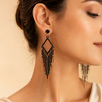 Woman wearing black chandelier fringe earring with gold spike charms, close-up on ear and neck, statement jewelry photo