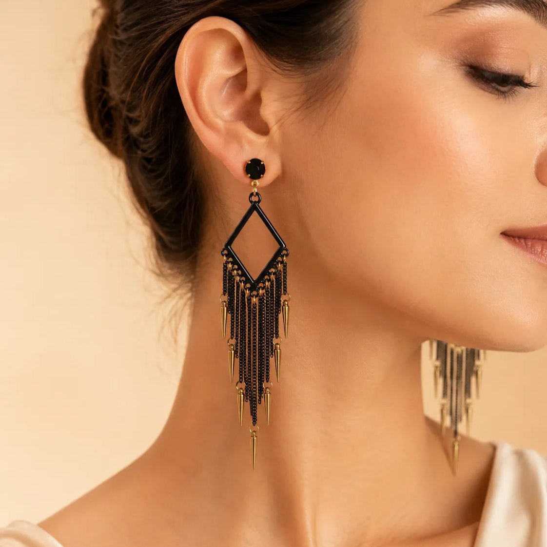 Woman wearing black chandelier fringe earring with gold spike charms, close-up on ear and neck, statement jewelry photo