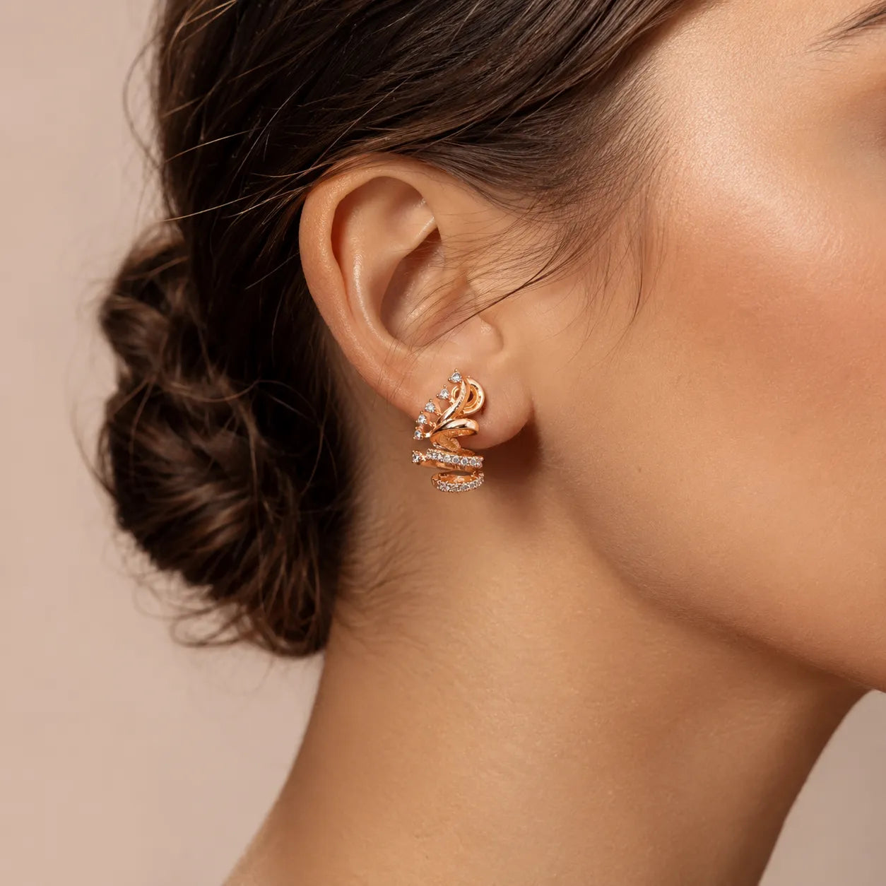 Woman wearing rose gold 3D sculptural spiral coil CZ crystal stud earrings styled with elegant updo hairstyle
