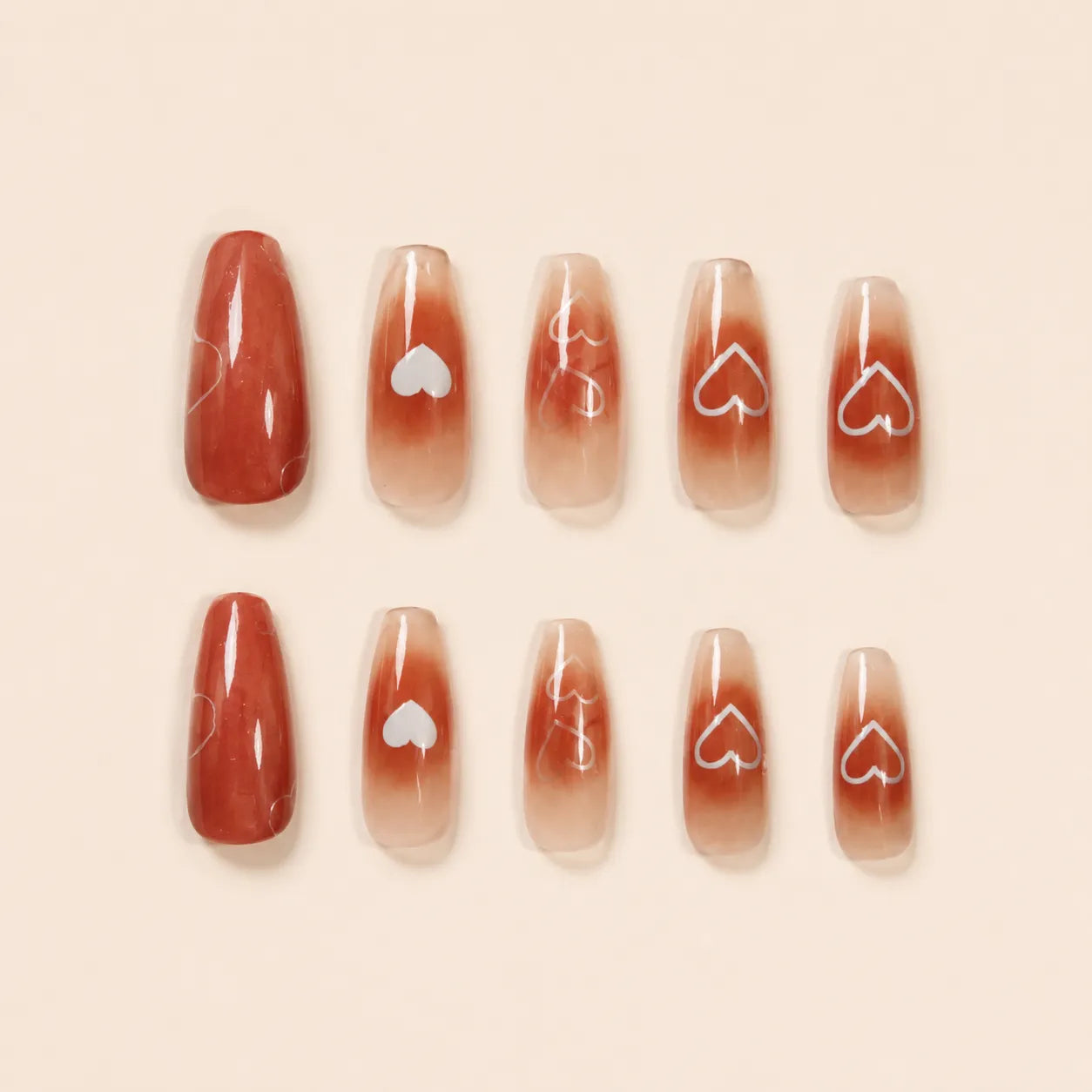 "Set of terracotta ombre press-on nails with white heart outline design"