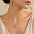 Woman wearing silver hexagon halo pendant necklace with round cut center stone, close-up on neckline