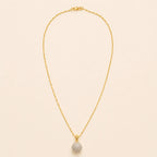 Gold plated paperclip chain necklace with pavé crystal ball pendant, full length view on beige background