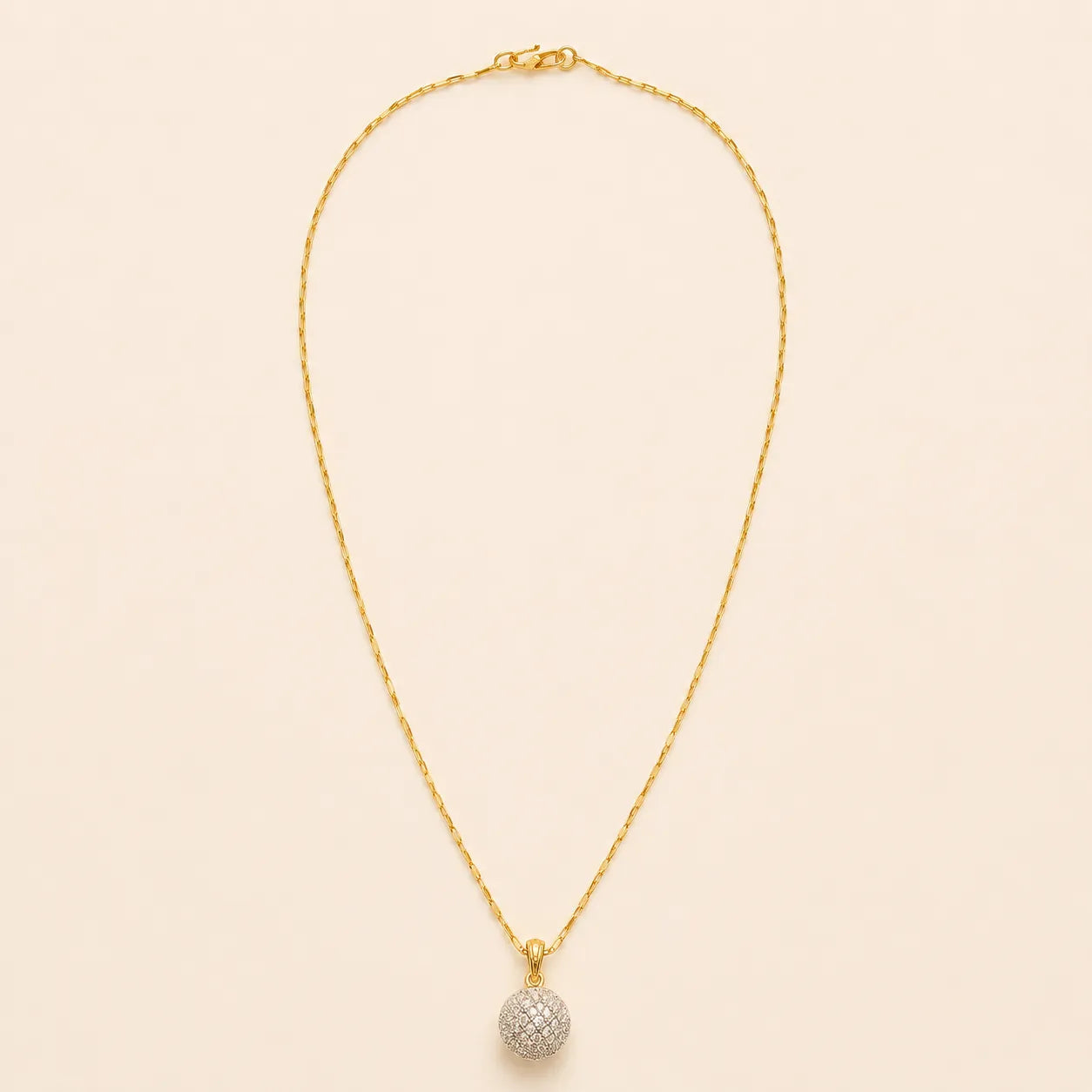 Gold plated paperclip chain necklace with pavé crystal ball pendant, full length view on beige background
