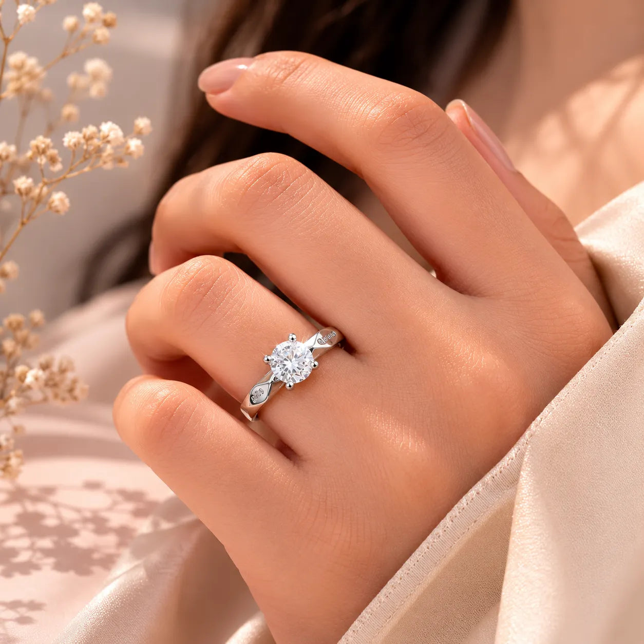 Woman wearing round cut solitaire engagement ring on ring finger, close-up showing engraved band detail