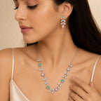 Woman wearing silver crystal vine necklace and floral drop earrings, close-up on neckline and ear