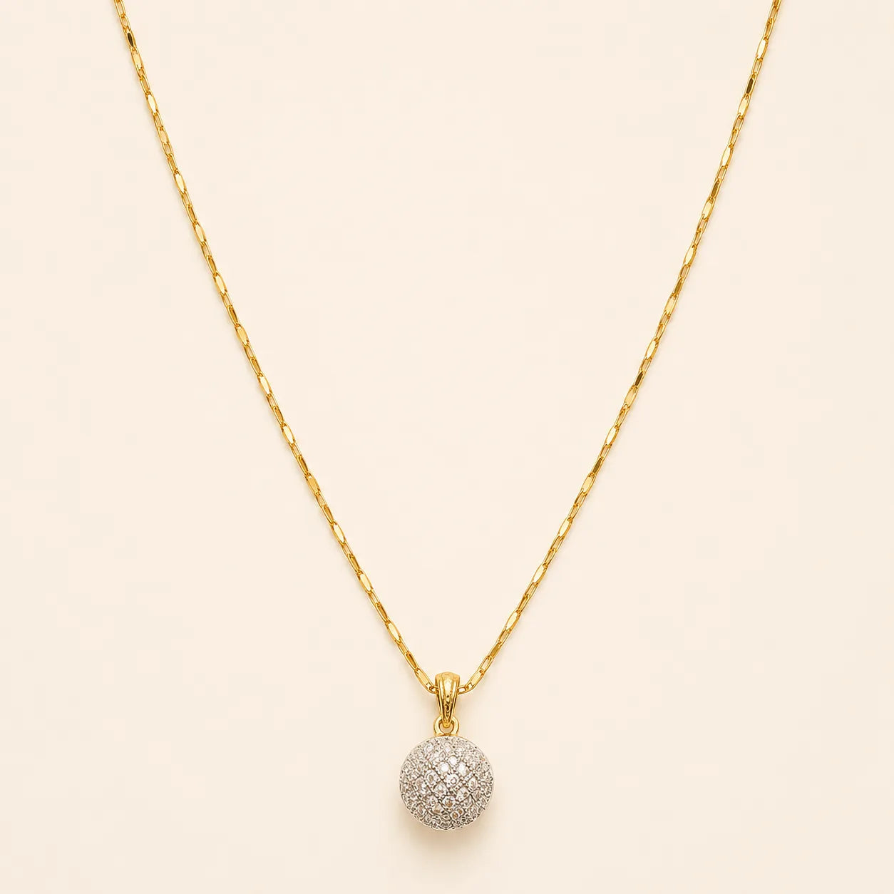 Close-up of gold necklace chain and sparkly pavé crystal ball pendant with lobster clasp detail