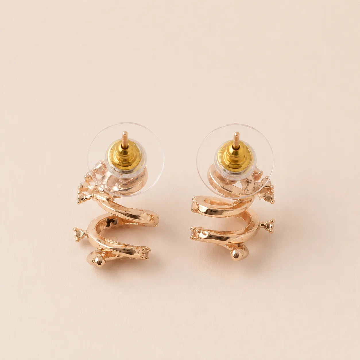 A pair of gold and rose gold spiral stud earrings with clear crystal accents, 