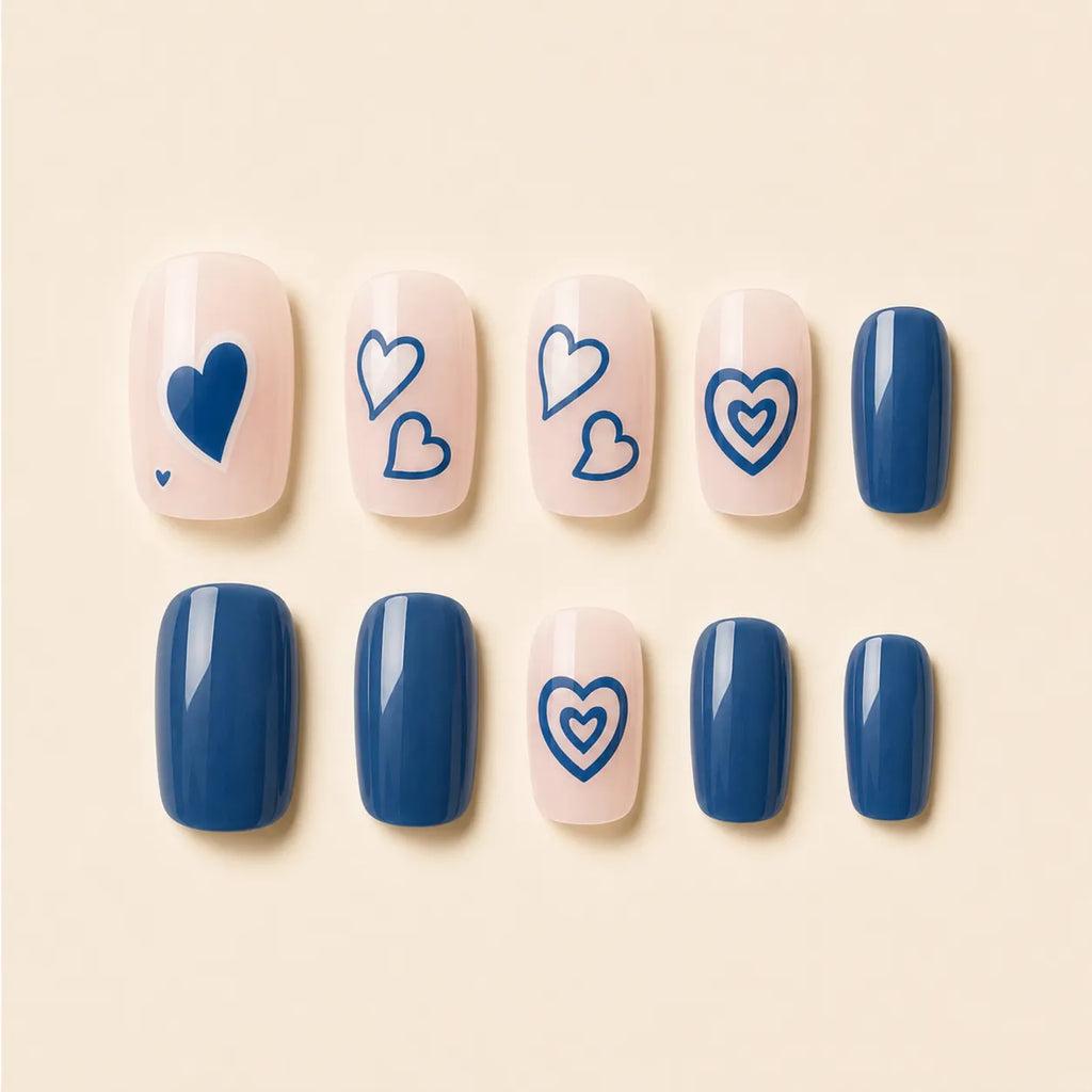 SAVNI navy blue press-on nails with heart nail art design, 10-piece glossy fake nail set on beige background