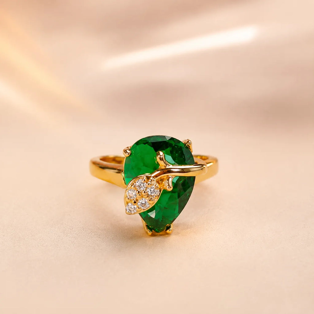"Close-up of emerald green pear cut ring with gold leaf and CZ diamond accents"