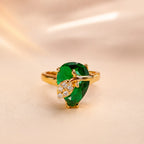 "Close-up of emerald green pear cut ring with gold leaf and CZ diamond accents"