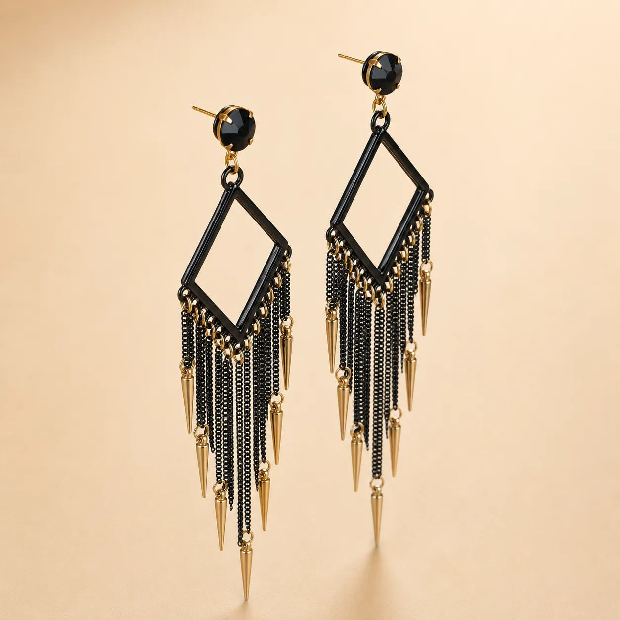 Black tassel fringe earrings with gold spike drops and black crystal top, angled product photo on beige background