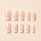  Ten French tip press on nails with nude pink base and white tips laid flat on beige background