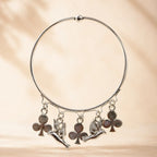 Side angle view of silver angel cherub and club charm bangle bracelet showing charm detail and ball bead top closure on warm background