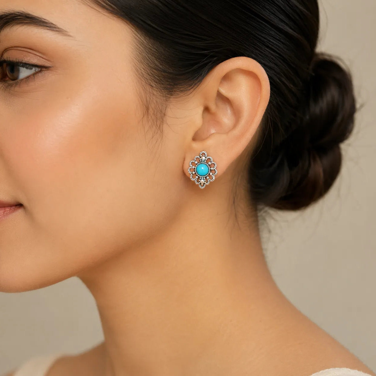 "Woman wearing silver filigree flower stud earring with turquoise center"