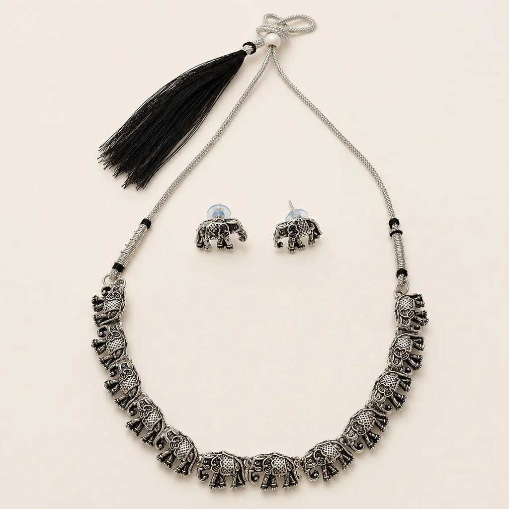 "Silver elephant necklace and earring set with black tassel on beige background"