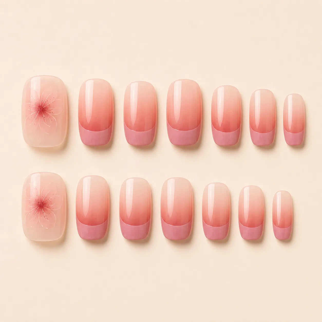 Set of 24 short square pink ombre French tip press-on nails with cherry blossom floral accent arranged in two rows on cream background