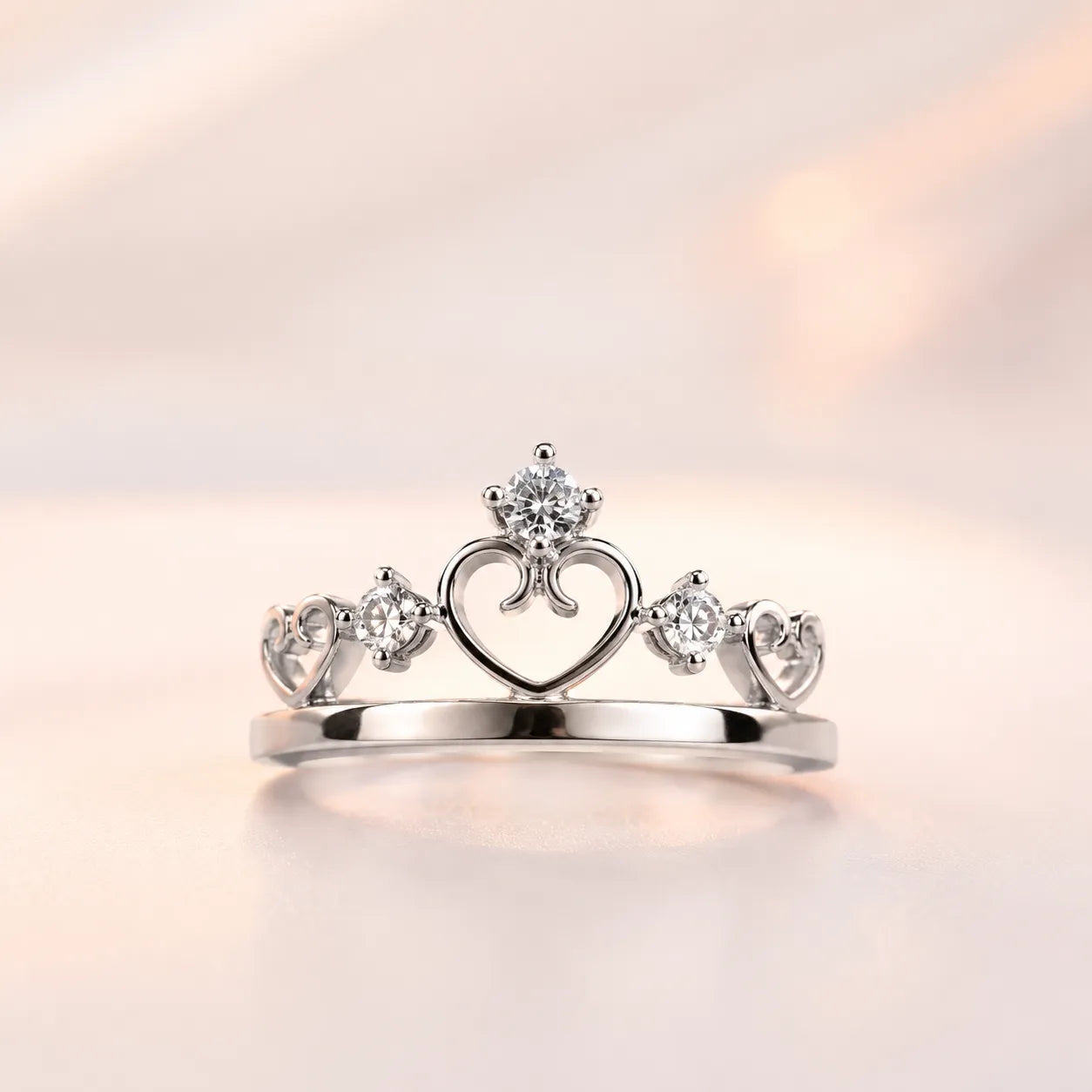 Silver princess crown tiara ring with open heart motif and CZ solitaire — her ring from couple matching set on blush background