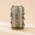 Angled view of silver broad kada bangle showing full circumference of white enamel crystal checkerboard pattern and cascading silver ghungroo ball fringe