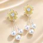 "Yellow enamel flower earrings with silver chain and pearl drops on silk fabric"